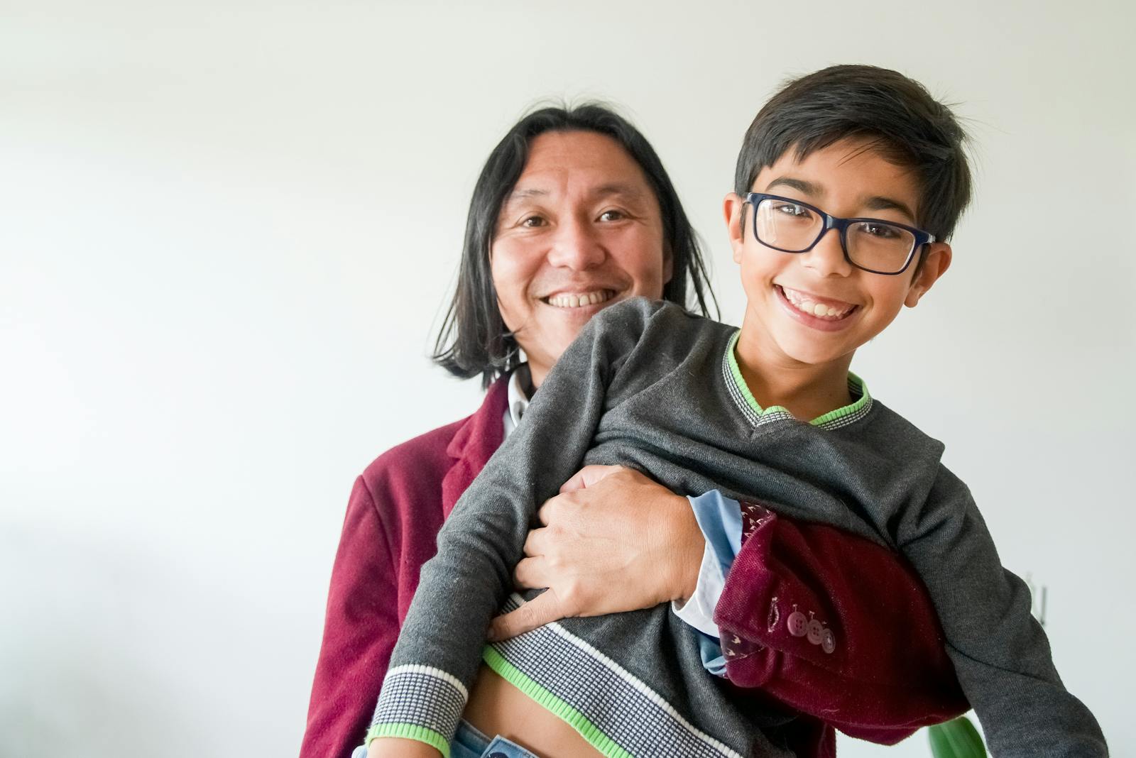 Cheerful father carrying his smiling son in a cozy indoor setting.