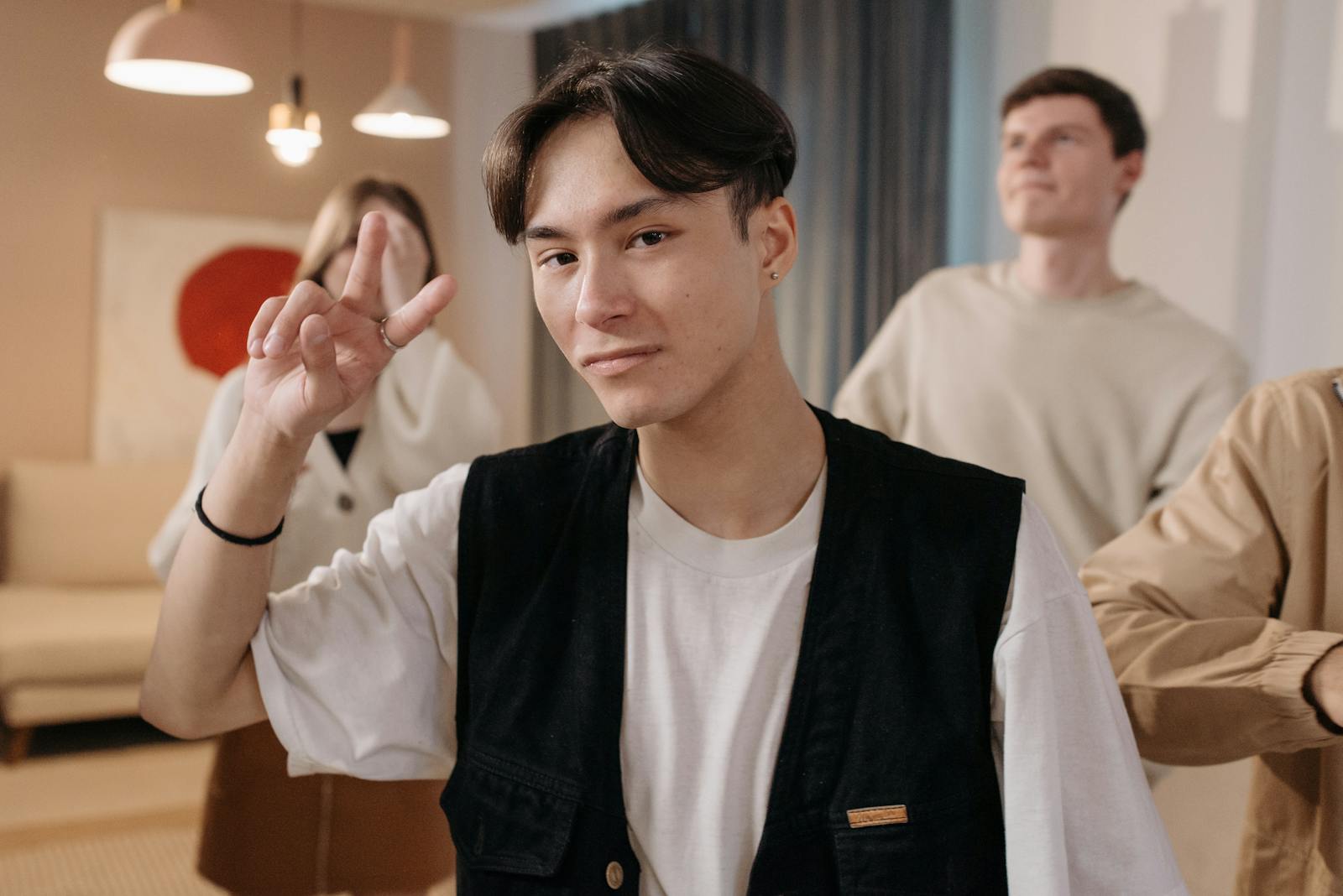 Young man making a peace sign, posing confidently in an indoor setting.