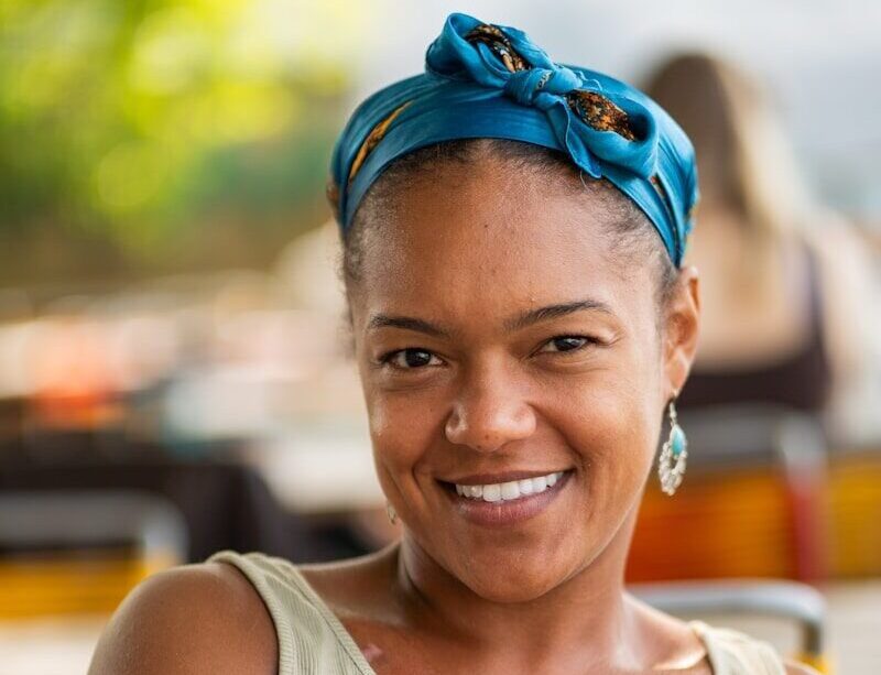 Smiling woman wearing a teal headscarf and tank top.